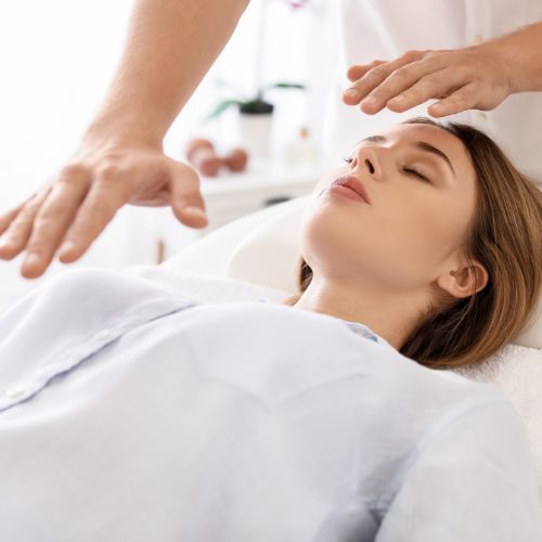 reiki stress relief treatment being performed on a female patient laying down